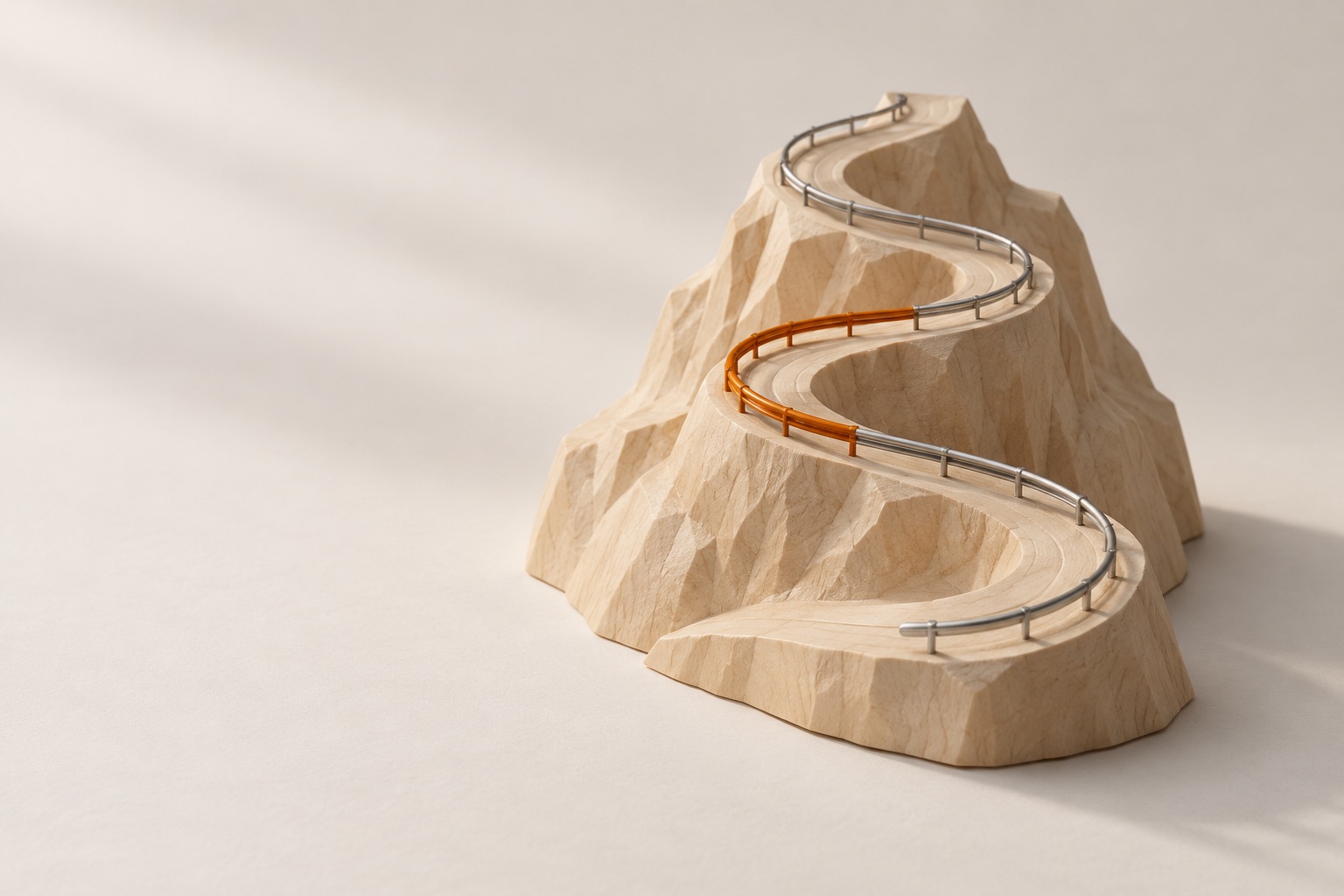 A small carved wooden model of a winding mountain road with a guardrail on each bend, one of them burnt orange.